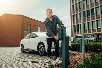 Mitarbeiter lädt seinen Firmenwagen an Ladestation auf Firmenparkplatz Mitarbeiter lädt seinen Firmenwagen an Ladestation auf Firmenparkplatz